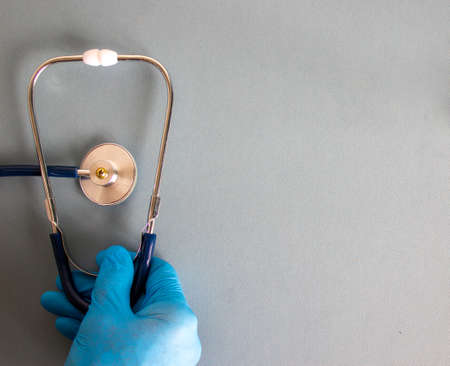 Doctor's hand with stethoscope on blue background. Medical and COVID-19 Pandemic Coronavirus concept. Copy space.の写真素材