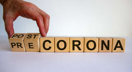 Hand turns cubes and changes the expression 'pre corona' to 'post corona'. Covid-19 pandemic concept. Beautiful white background. Copy space.の写真素材