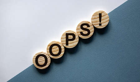 Wood circles with word 'oops' on paper white and blue background, copy space. Business concept.の写真素材