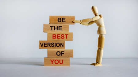 Concept of building success foundation. Wooden blocks on the stack of wooden blocks. Wooden model of human. Text 'be the best version of you'. Beautiful white background, copy space.の写真素材