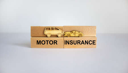 Wooden blocks with words 'motor insurance', wooden models of car. Beautiful white background. Copy...