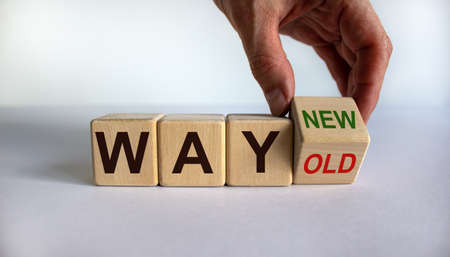 Hand turns a cube and changes the words 'way old' to 'way new'. Business concept. Beautiful white background, copy space.の写真素材