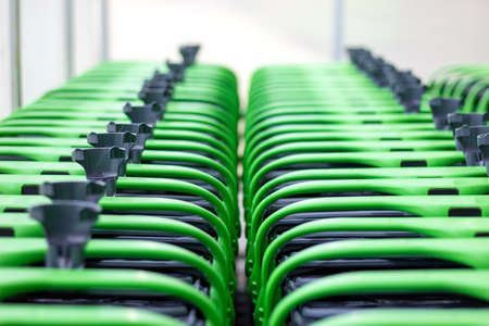 Rows of shopping trolleys outside supermarket. Green shopping carts together in a line up.