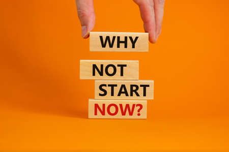 Male hand placing a block with word 'why' on a blocks tower with words 'why not start now'....