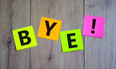 Colored paper with word 'bye' on beautiful wooden background, copy space. Business concept.の写真素材