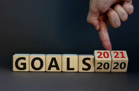 Hand turns cubes and changes the expression 'goals 2020' to 'goals 2021'. Beautiful gray background....