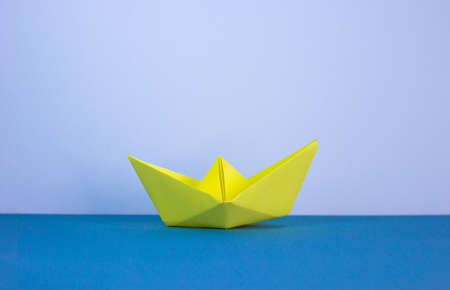 Image of paper made origami boat on beautiful blue table, white background with copy space. Business concept.の写真素材