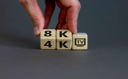 Symbol of the change from 4K TV to 8K TV. Male hand. Beautiful gray background, copy space.の写真素材