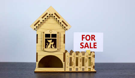 Words 'for sale' on white paper card. Model of a wooden house. Copy space. Business concept....