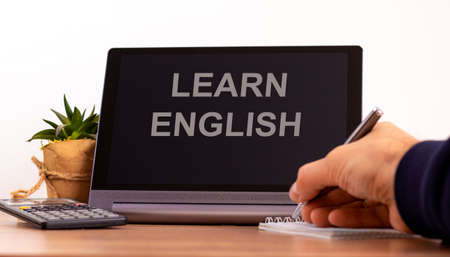 Education concept. Tablet with text 'learn english'. Male hand with pen, calculator, copy space.の写真素材
