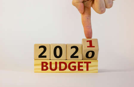 Business concept of budget planning 2021. Male hand flips wooden cube and changes the inscription...