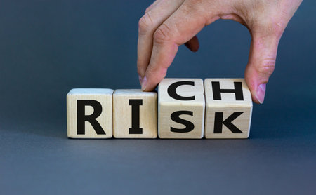 Take a risk and getting rich concept. Hand flips a cube and changes the word 'risk' to 'rich' or vice versa. Beautiful gray background. Business concept. Copy space.の写真素材