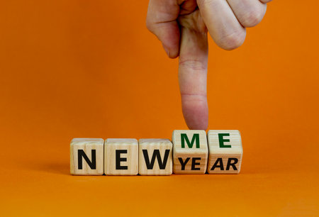 New year time. Male hand turns cubes and changes the words 'new year' to 'new me'. Beautiful orange background. Copy space. Business and new year - new me concept.の写真素材