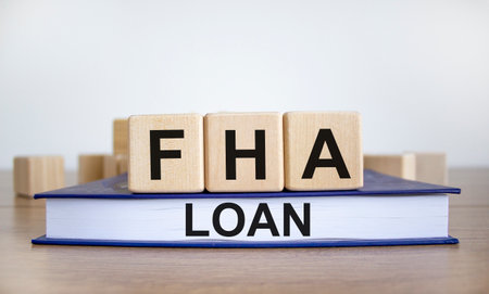 FHA loan symbol. Wooden blocks form the words 'FHA loan', book, wooden table. Beautiful white background, copy space. Business and FHA - federal housing administration loan concept.の写真素材