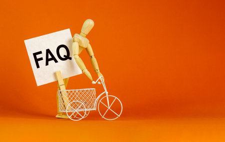 FAQ, frequently asked questions symbol. White paper. Words 'FAQ, frequently asked questions'. Miniature bicycle, wooden human. Beautiful orange background. Business and FAQ concept, copy space.の写真素材