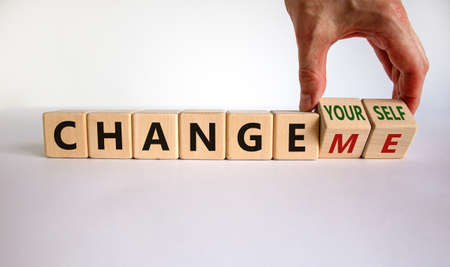 Change yourself or me symbol. Businessman turns wooden cubes and changes words 'change me' to 'change yourself'. Beautiful white background, copy space. Business and change yourself concept.の写真素材