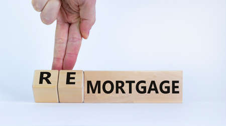 Mortgage or remortgage symbol. Businessman turns cubes and changes the word 'remortgage' to 'mortgage'. Beautiful white background, copy space. Business, Mortgage or remortgage concept.の写真素材