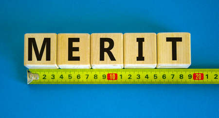 Merit symbol. Wooden cubes with the word 'merit'. Beautiful blue background, copy space. Yellow...