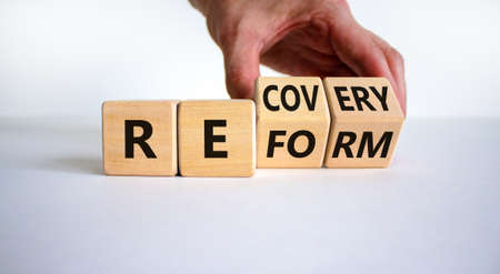 Recovery and reform symbol. Businessman turns cubes and changes the word 'recovery' to 'reform'. Beautiful white background. Business and recovery - reform concept. Copy space.の写真素材