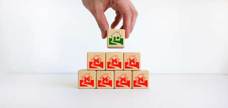 Businessman placing a cube with house sign near of a other cubes. Cubes with abandoned house icons....