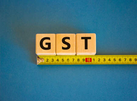 GST, goods and services tax symbol. The word GST, goods and services tax on cubes arranged behind...