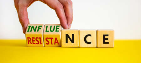 Influence or resistance symbol. Businessman turns cubes, changes the word 'resistance' to 'influence'. Beautiful white background. Copy space. Business and influence or resistance concept.の写真素材