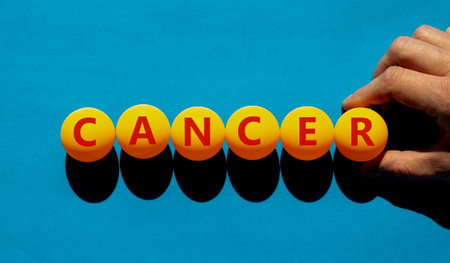 Medical and cancer symbol. The concept word 'cancer' on orange table tennis balls on a beautiful blue background. Doctor hand. Medical and cancer concept.の写真素材