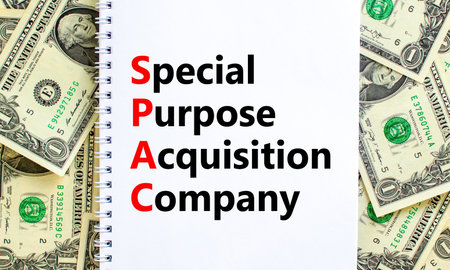 SPAC, special purpose acquisition company symbol. Words SPAC, special purpose acquisition company on white note on beautiful background from dollar bills. Business and SPAC vs IPO concept. Copy space.の写真素材