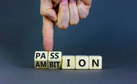 Passion or ambition symbol. Businessman turns wooden cubes and changes the word 'ambition' to 'passion'. Beautiful gray table, gray background, copy space. Business, passion or ambition concept.の写真素材