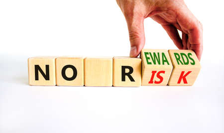 No risk and rewards symbol. Businessman turns wooden cubes and changes words 'no risk' to 'no rewards'. Beautiful white background. No risk and rewards, business concept. Copy space.の写真素材