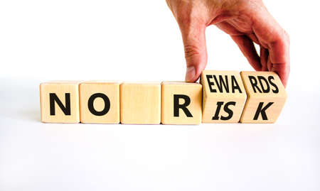 No risk and rewards symbol. Businessman turns wooden cubes and changes words 'no risk' to 'no rewards'. Beautiful white background. No risk and rewards, business concept. Copy space.の写真素材