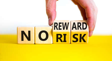 No risk or reward symbol. Businessman turns wooden cubes and changes words 'no risk' to 'no reward'. Beautiful white background. No risk or reward and business concept. Copy space.の写真素材