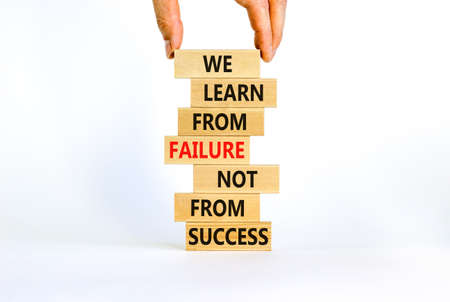 Failure or success symbol. Wooden blocks with words We learn from failure not from success. Beautiful white background, copy space. Businessman hand. Business, learn from failure or success concept.の写真素材