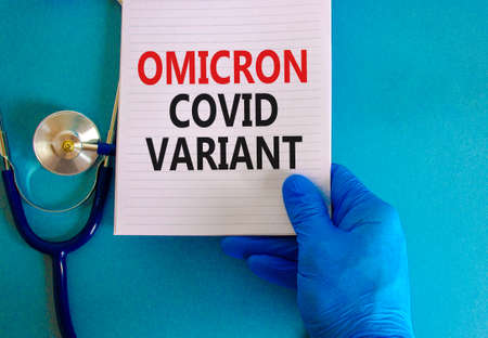 New covid-19 omicron variant strain symbol. Hand in blue glove with white note. Concept words Omicron covid variant. Stethoscope. Medical and COVID-19 omicron variant strain concept. Copy space.の写真素材