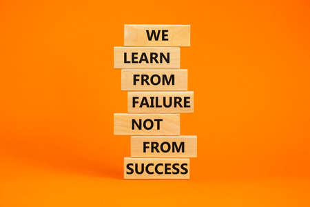 Failure or success symbol. Wooden blocks with words We learn from failure not from success. Beautiful orange background, copy space. Business, learn from failure or success concept.の写真素材