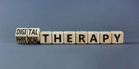 Physical or digital therapy symbol. Turned wooden cubes and changed words physical therapy to digital therapy. Beautiful grey background. Medical, physical or digital therapy concept. Copy space.の写真素材