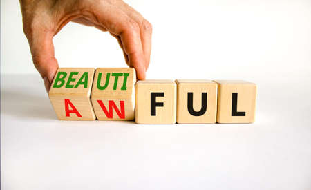 Beautiful or awful symbol. Businessman turns wooden cubes, changes the word Awful to Beautiful. Beautiful white background, copy space. Business, psychological beautiful or awful concept.の写真素材