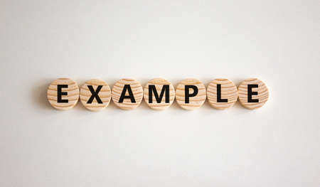 Example symbol. The concept word Example on wooden circles. Beautiful white background, copy space....