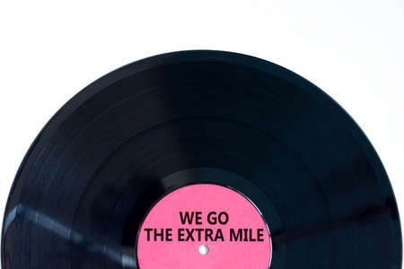 We go the extra mile symbol. Concept words We go the extra mile on retro black vinyl disc. Beautiful white background, copy space. Business and we go the extra mile concept.の写真素材