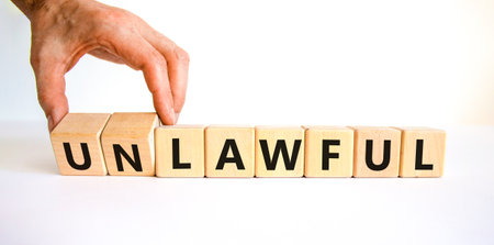 Lawful or unlawful symbol. Businessman turns wooden cubes and changes the word unlawful to lawful. Beautiful white table, white background, copy space. Business and lawful or unlawful concept.の写真素材