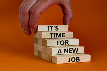 It is time for a new job symbol. Wooden blocks with words It is time for a new job. Beautiful orange background, copy space. Businessman hand. Business, time for a new job concept.の写真素材
