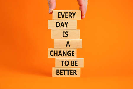 Change to be better symbol. Wooden blocks with words Every day is a change to be better. Beautiful orange background, copy space. Businessman hand. Business, motivational change to be better concept.の写真素材