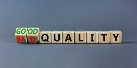 Good or bad quality symbol. Turned wooden cubes and changed words bad quality to good quality. Beautiful grey table grey background. Business good or bad quality concept, copy space.の写真素材