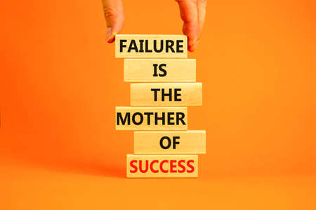 Failure or success symbol. Wooden blocks with words A failure is the mother of success. Beautiful orange table orange background. Businessman hand. Business, failure or success concept. Copy space.の写真素材