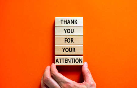 Thank you for attention symbol. Concept words Thank you for your attention on wooden blocks on beautiful orange table orange background. Businessman hand. Business and thank you for attention concept.の写真素材