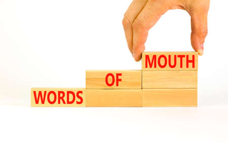 Words of mouth symbol. Concept words Words of mouth on wooden blocks on a beautiful white table white background. Businessman hand. Business, finacial and words of mouth concept. Copy space.の写真素材