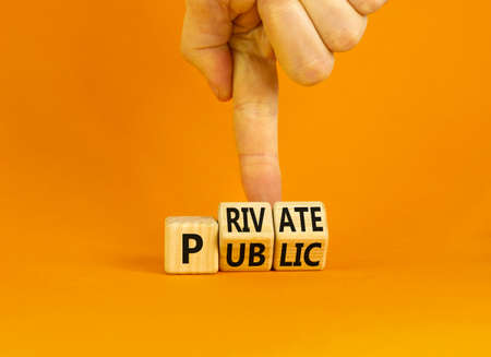 Private or public symbol. Concept words Private or Public on wooden cubes. Businessman hand. Beautiful orange table orange background. Business and private or public concept. Copy space.の写真素材