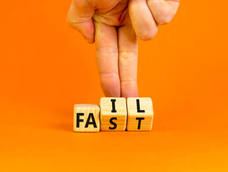 Fail fast symbol. Concept words Fail fast on wooden cubes. Businessman hand. Beautiful orange table orange background. Business and fail fast concept. Copy space.の写真素材