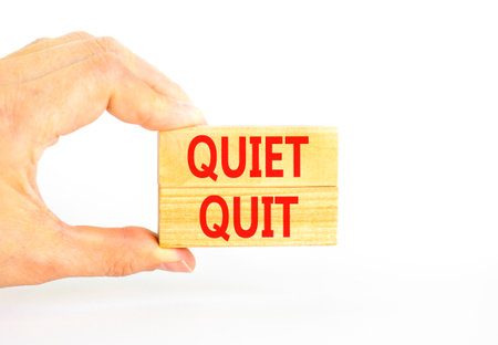 Quiet quit symbol. Concept words Quiet quit on wooden blocks. Beautiful white table white background. Businessman hand. Business and quiet quit concept. Copy space.の写真素材