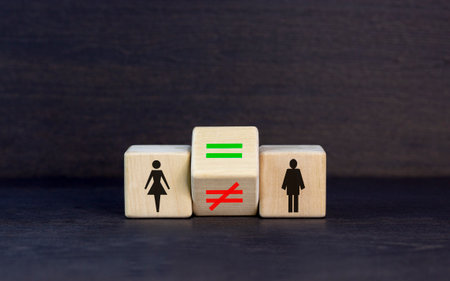Symbol for gender equality. Turned a cube and changed a unequal sign to a equal sign between symbols of men and women. Beautiful black table black background, copy space. Gender equality concept.の写真素材